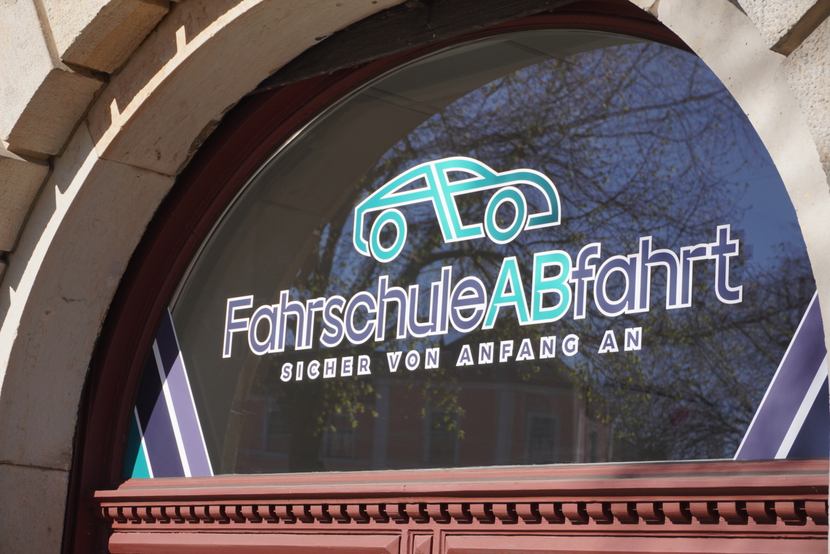 Ben von Fahrschule Abfahrt erklärt die Vorfahrt an einer Kreuzung an einer Tafel