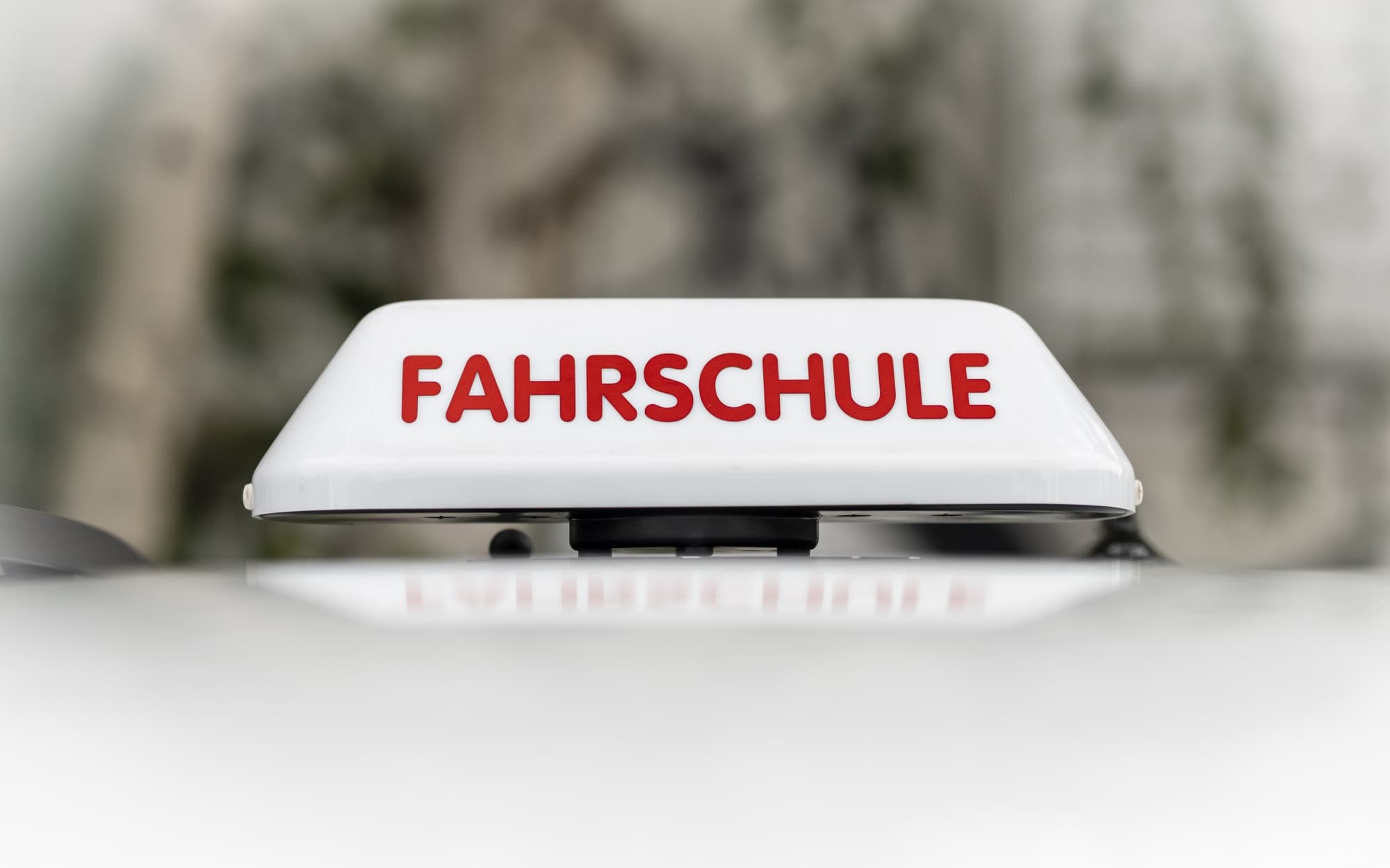 Ein Fahrschulschild, welches auf einen Fahrschulauto von Fahrschule ABfahrt aufweist.